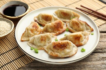 Delicious fried gyoza dumplings with green onions served on table, closeup