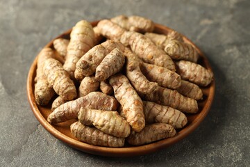 Raw tumeric rhizomes on grey table, closeup