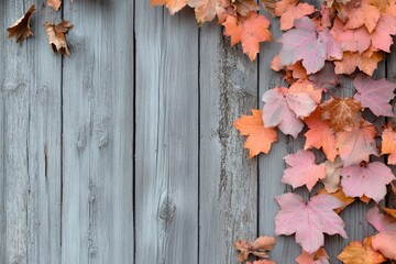 Autumn leaves of various shades of orange and pink adorn a rustic gray wooden fence.