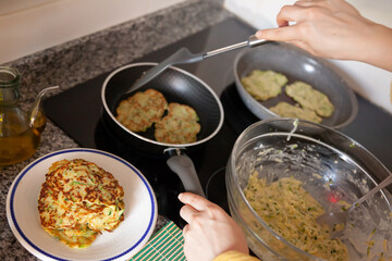 Cooking at home. Frying of appetizing vegetarian zucchini fritters