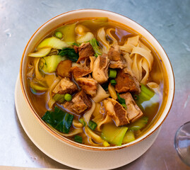 Taiwanese soup containing beef, noodle, tomato, mustard cabbage and green onion