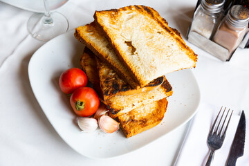 Crispy toasted white bread slices, fresh ripe tomatoes and garlic served on plates. Ingredients for traditional Catalan tapas Pan con tomate