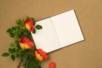 Open empty notebook with flowers on fabric background. Flat lay, top view. Copy space
