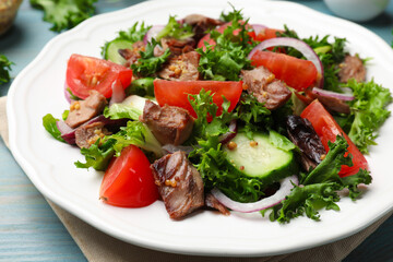 Delicious fresh tuna salad on light blue wooden table, closeup