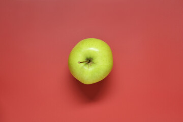 Fresh green apple on red background, top view