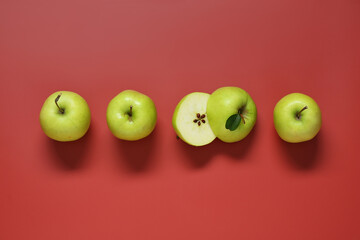Whole and cut apples on red background, flat lay