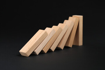 Domino effect. Wooden blocks falling on black background