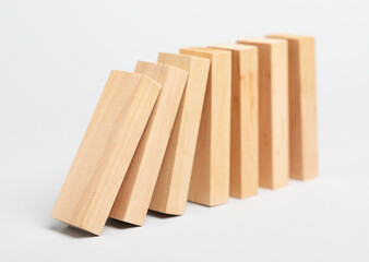Domino effect. Wooden blocks falling on light background