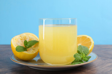 Glass of lemon juice and fresh fruits on wooden table, closeup