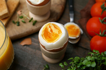 Soft boiled egg, microgreens and tomatoes on wooden table, closeup