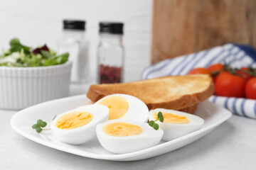Hard boiled eggs with bread on light table, closeup