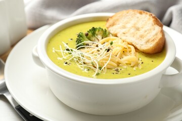 Delicious broccoli cream soup served on table, closeup