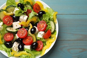 Delicious fresh Greek salad on light blue wooden table, top view. Space for text