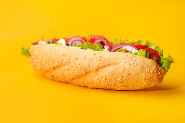 Delicious baguette with salmon on yellow background, closeup