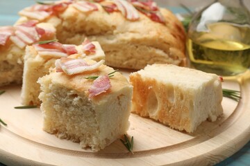 Pieces of delicious focaccia bread with bacon served on blue wooden table, closeup