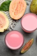 Refreshing guava juice and fresh fruits on grey table, flat lay