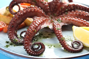 Fried octopus with herb sauce and lemon on table, closeup