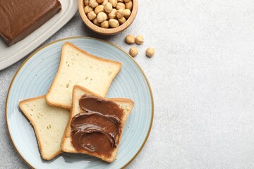 Sandwiches with chocolate butter and hazelnuts on grey table, flat lay. Space for text