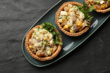Tartlets with delicious filling on black table, top view