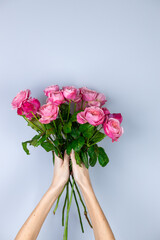 on a light gray background on the outstretched arms of a girl pink peony roses March 8 women's holiday first date favorite flowers