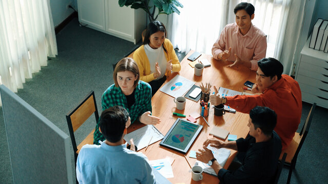 Top view of attractive diverse team clapping hands while project manager present creative idea at meeting room. Diverse team working together planning marketing strategy at meeting room. Convocation.