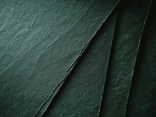 Close-up of overlapping dark green slate sheets forming diagonal lines, highlighting the natural texture and pattern of the stone, suitable for backgrounds and design projects
