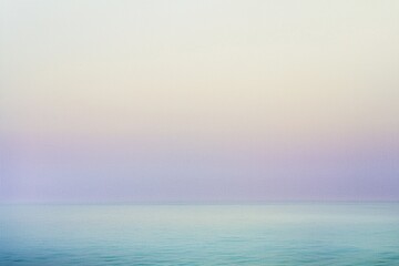 Fototapeta premium Soft pastel colors blend seamlessly in the sky above a tranquil ocean, creating a serene and minimalist seascape at sunrise, evoking a sense of peace and tranquility