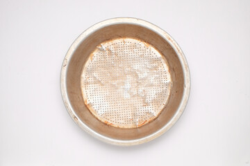 Coconut milk strainer made from aluminum which has been used isolated on a white background. Traditional coconut milk strainer. Yellow crusty. For graphic design or banner background