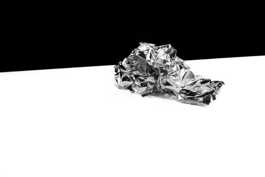 A ball of aluminum foil on a white table against a black backdrop