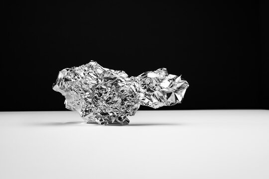 A ball of aluminum foil on a white table against a black backdrop