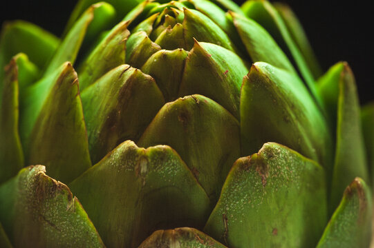 Closeup overhead shot of a raw artichoke against a black background