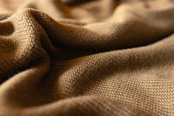 Side view brown coloured knitted fabric with waves and selective blur.