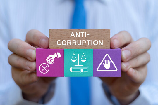 Business person holding colorful blocks with icons sees inscription: ANTI-CORRUPTION. Concept of anti corruption activities that oppose or inhibit corruption. International anti-corruption day. - Powered by Adobe