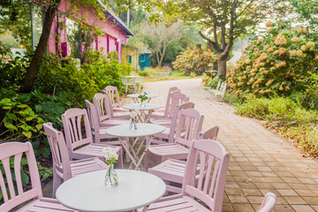 Pink chairs and round tables arranged on a floral patio, offering serene seating.