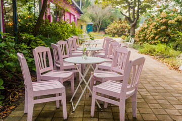Outdoor seating arrangement with pink chairs and tables in a charming garden setting.