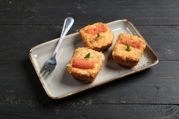 Close-up of traditional Indonesian fried stuffed tofu (Tahu Fantasi) served on a ceramic plate over a dark wooden background.