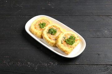 Rolled omelette slices filled with mixed vegetables and herbs, beautifully plated with parsley garnish, traditional Asian style savory snack or appetizer on dark background.