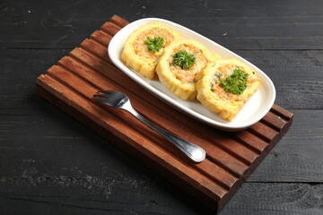 Close-up of rolled omelette stuffed with vegetables, served on a white plate with parsley garnish on dark wooden background. traditional Asian savory egg roll dish.