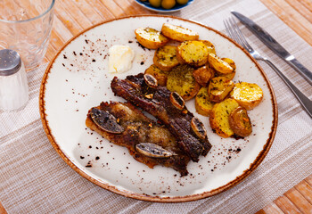 Fresh grilled beef rib steak, churrasco de ternera, served on table with roasted potatoes.