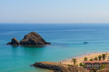 Snoopy Island in Fujairah, UAE. Aerial view of the beach with turquoise waters, a rocky island and a resort nearby