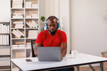 Fototapeta premium African American freelancer business man wearing headphones, enjoying working on laptop at workplace office.