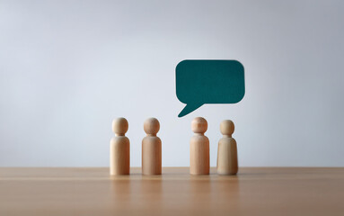Four wooden figurines stand in a row, facing a blank speech bubble.
