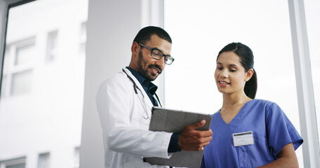 Fototapeta premium Healthcare, doctors and tablet in hospital for discussion, patient update or medical research. Below, man and nurse in clinic lobby for information report, good news or surgery feedback on technology