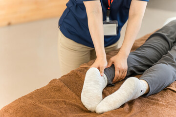 シニア女性をマッサージするあん摩マッサージ指圧師・理学療法士の女性
