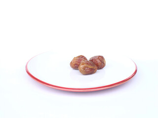 three dates in a plate on a white background