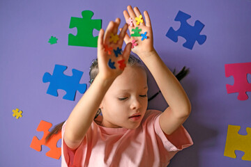 A thoughtful sad lonely girl with pieces of colored puzzles in her hands. Intellectual development of education. Problems of social behavior of children with autism