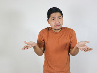I don't know. Young man isolated on grey background being at a loss, showing helpless gesture with...