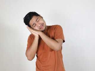 unhappy dreamy asian man, hold his hands near cheek, is nap, sleeping, daydreaming, making sleep gesture, standing over isolated white background with closed eyes
