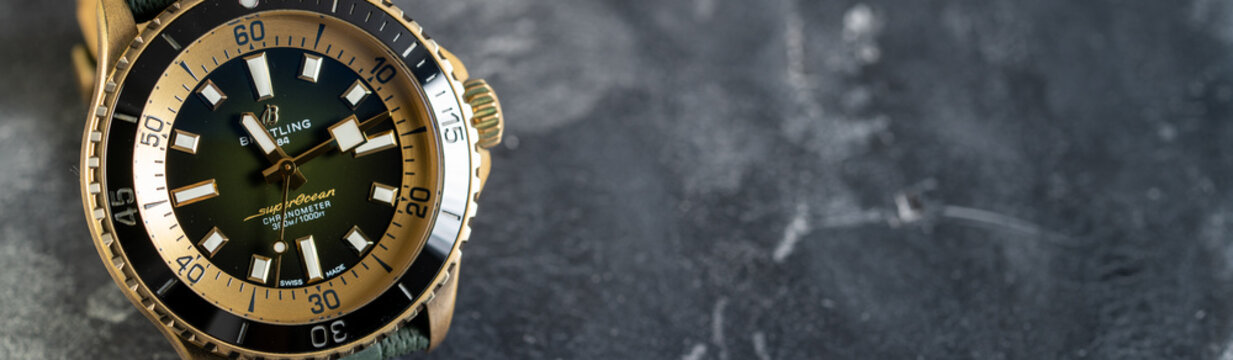 Swiss made golden Breitling Super Ocean luxury wrist watch on black stone background, copy space for text
