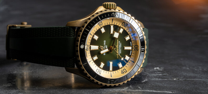 Swiss made golden Breitling Super Ocean luxury wrist watch on black stone background, copy space for text